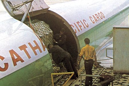 一张颗粒感强烈的复古照片，呈现一架国泰航空飞机停在跑道上，背景是连绵的山峦。